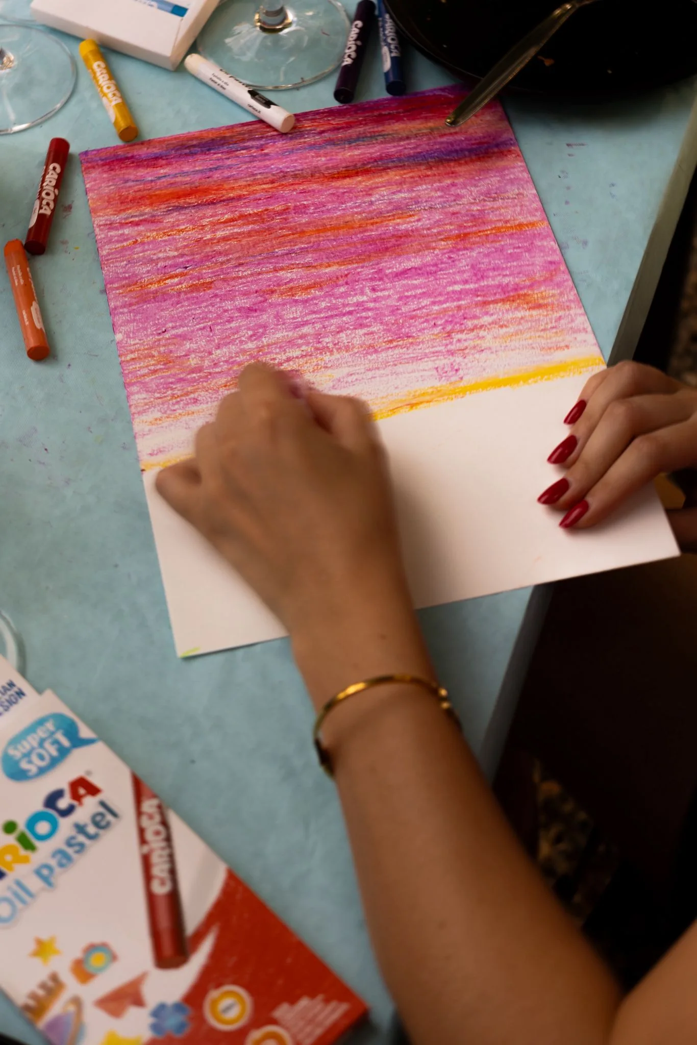 Mani che disegnano con pastelli colorati durante un laboratorio creativo